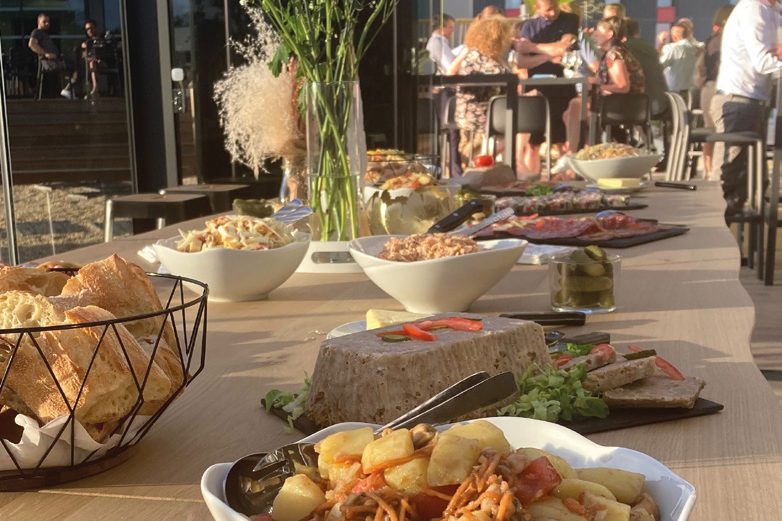 Buffet dressé en terrasse : salades, charcuteries et bouquet de fleurs