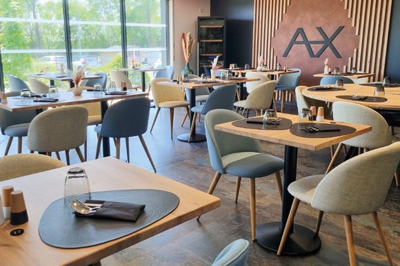 Salle du restaurant, tables en bois clair et chaises en velours