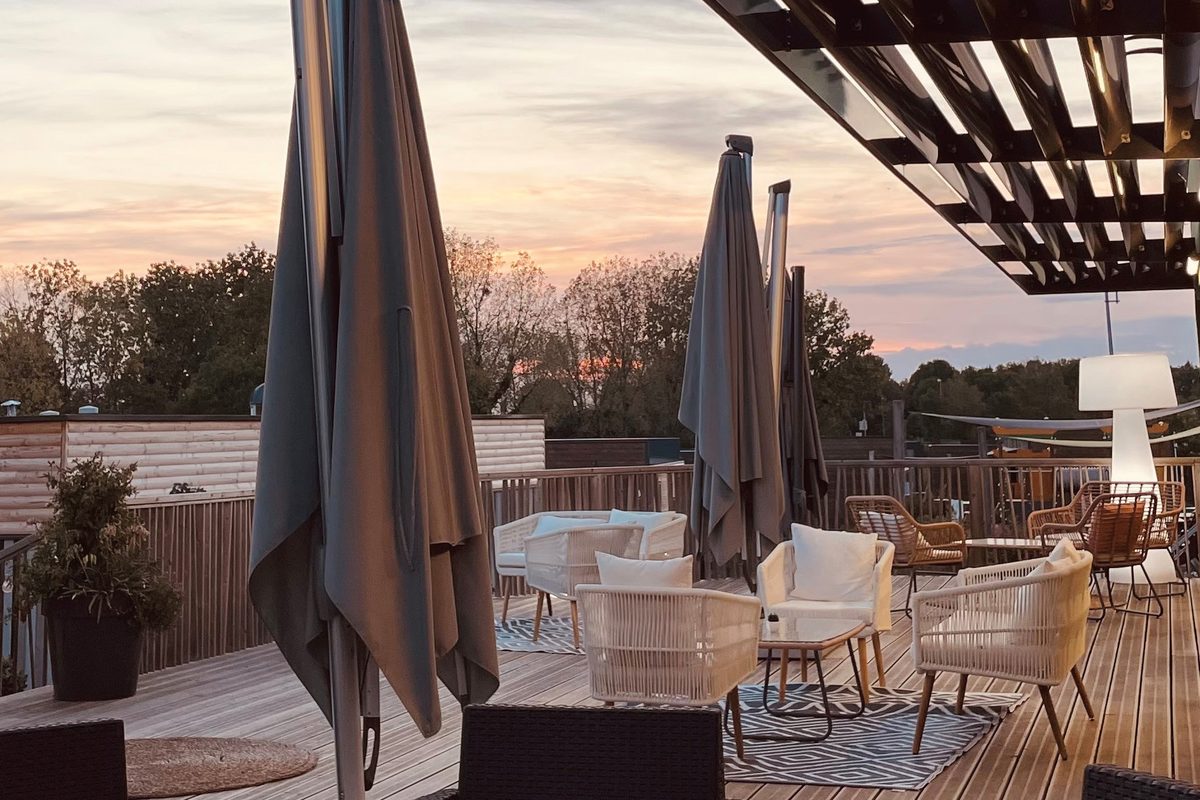 Terrasse en bois au coucher du soleil avec fauteuils et parasols