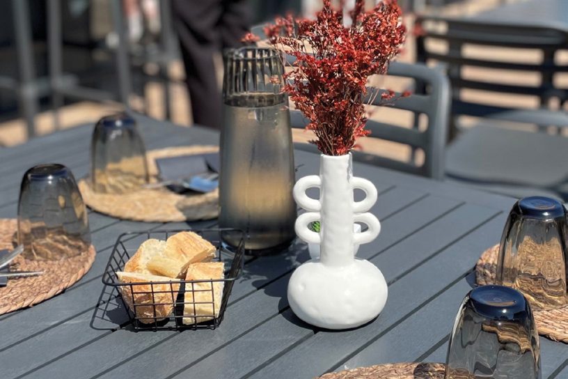 Table dressée en terrasse avec un vase de fleurs séchées