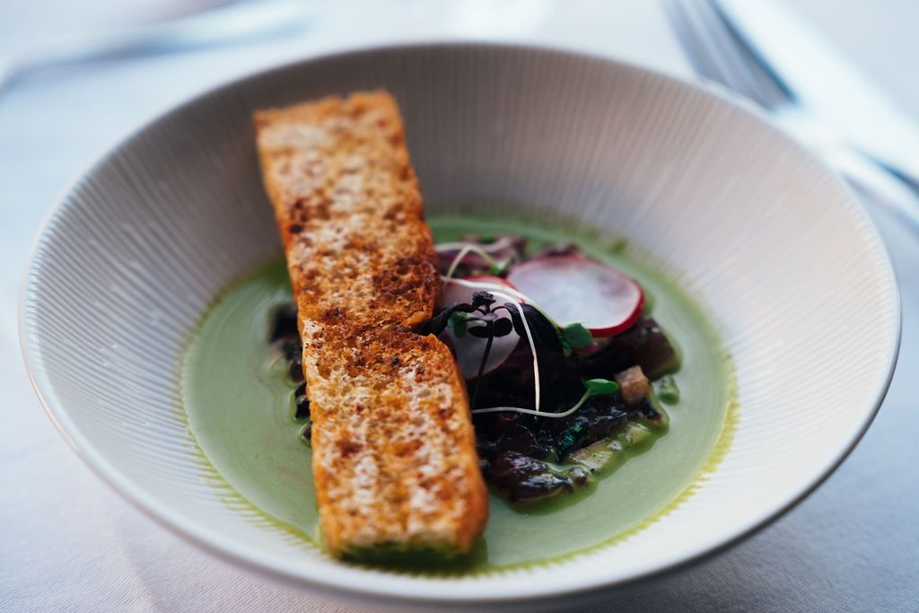 Assiette de poisson grillé sur un bouillon vert, servie à bord