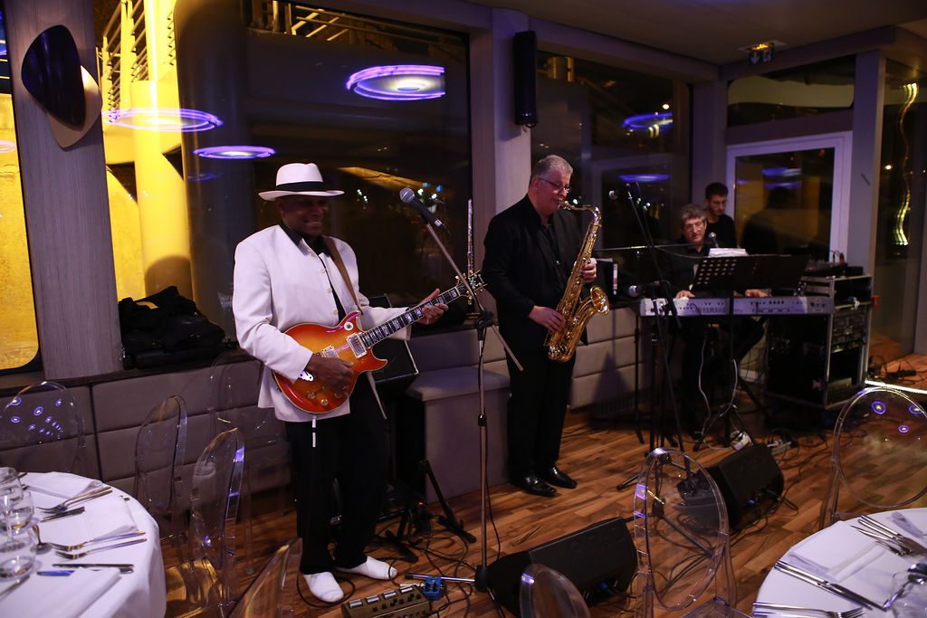 Un groupe de musiciens, guitare et saxophone, joue pendant le dîner