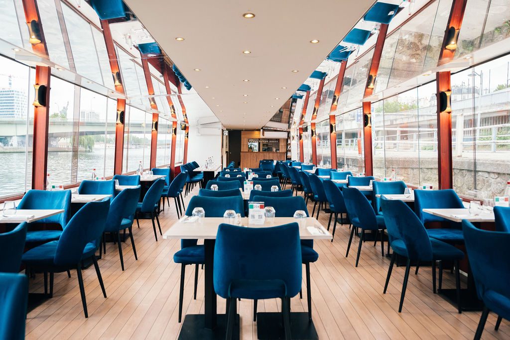 La salle panoramique du Théo, fauteuils bleus et tables blanches le long des baies vitrées