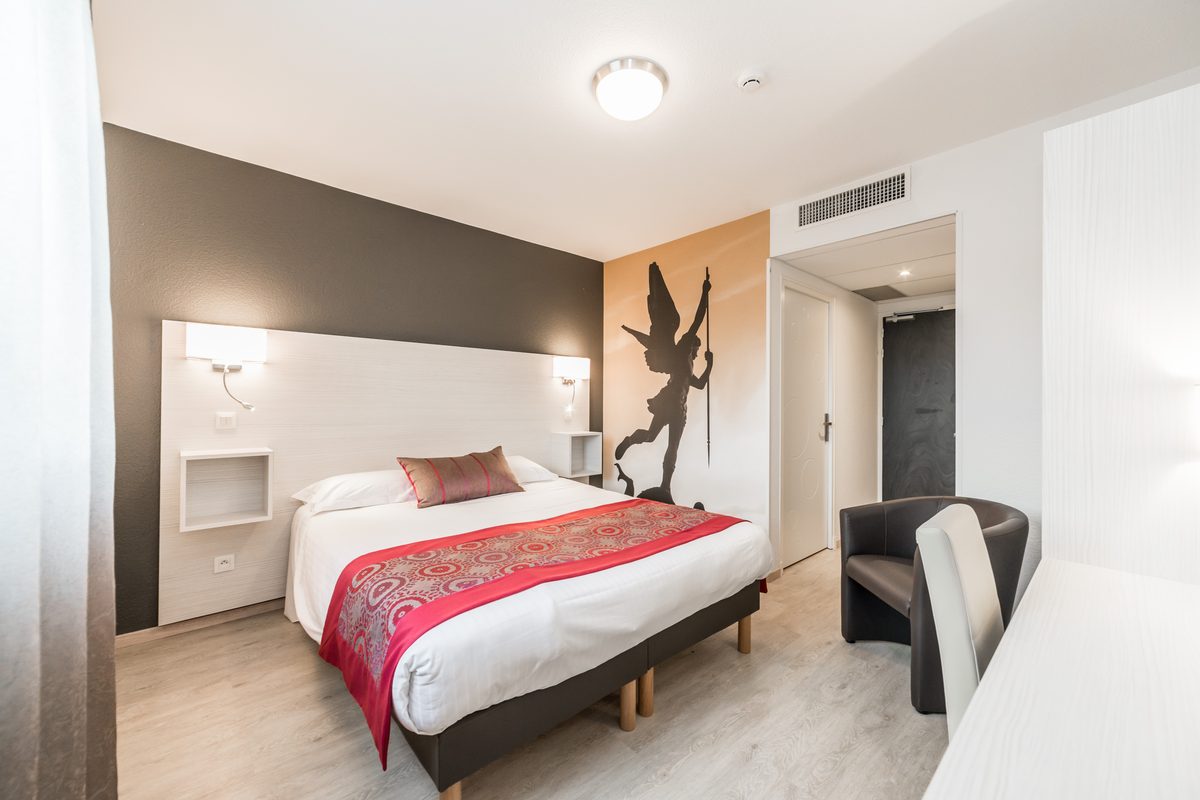 Chambre Confort : grand lit au jeté de lit rouge, fauteuil, décor gris et cuivré