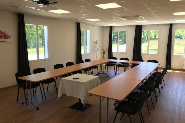 La salle de séminaire vue depuis l'écran, grandes fenêtres ouvertes sur la verdure