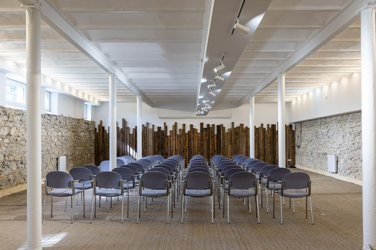 Salle Lavande : grande salle aux murs de pierre et colonnes blanches, chaises disposées en théâtre