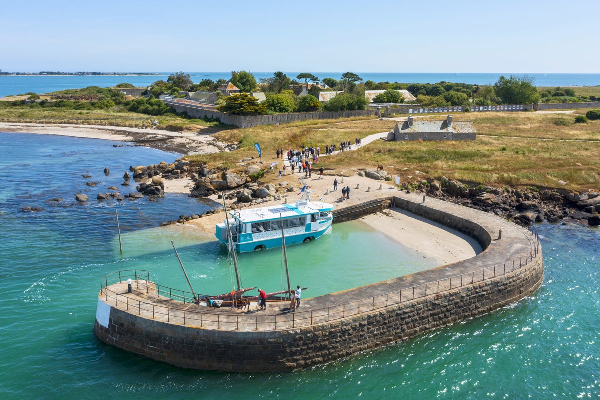 Le bateau amphibie à quai dans le petit port de l'île, eau turquoise