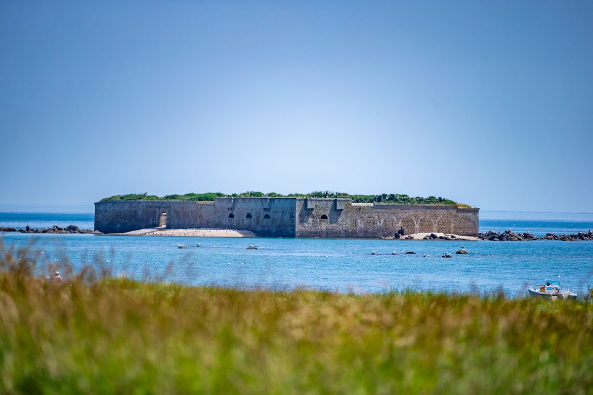 Un fort de pierre au large, vu depuis les prairies de l'île