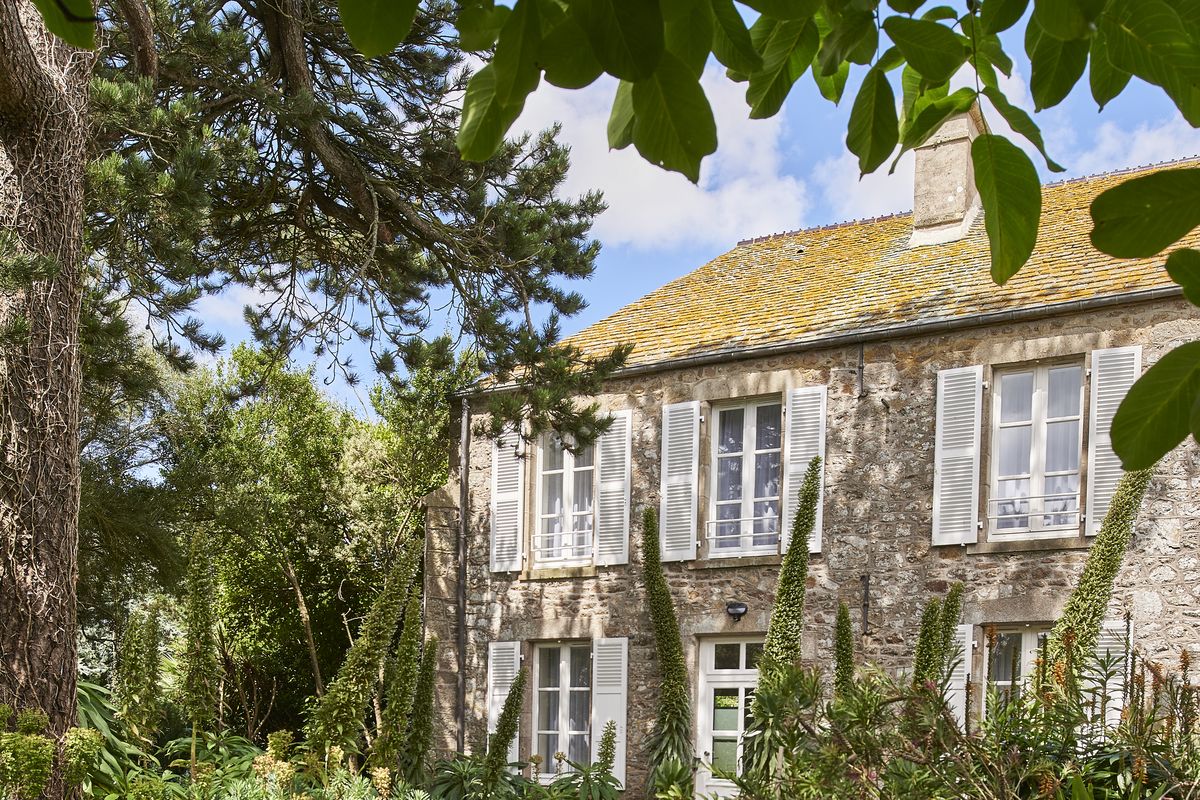 Façade en pierre de la Maison des Amiraux, entourée d'arbres