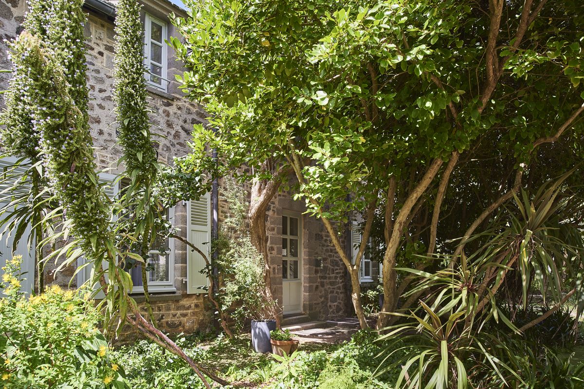 Façade en pierre de la Maison des Gabiers, entourée de végétation