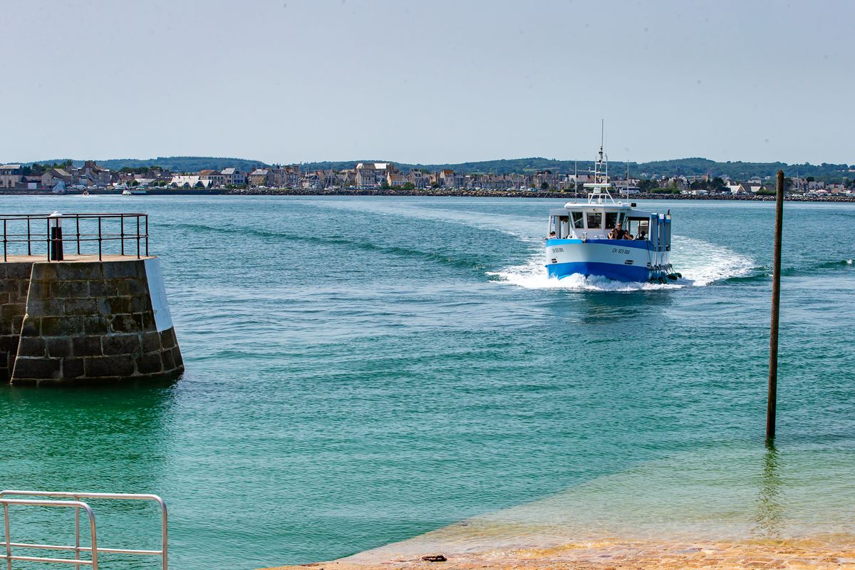 Le bateau traversant vers l'île, la côte de Saint-Vaast en arrière-plan